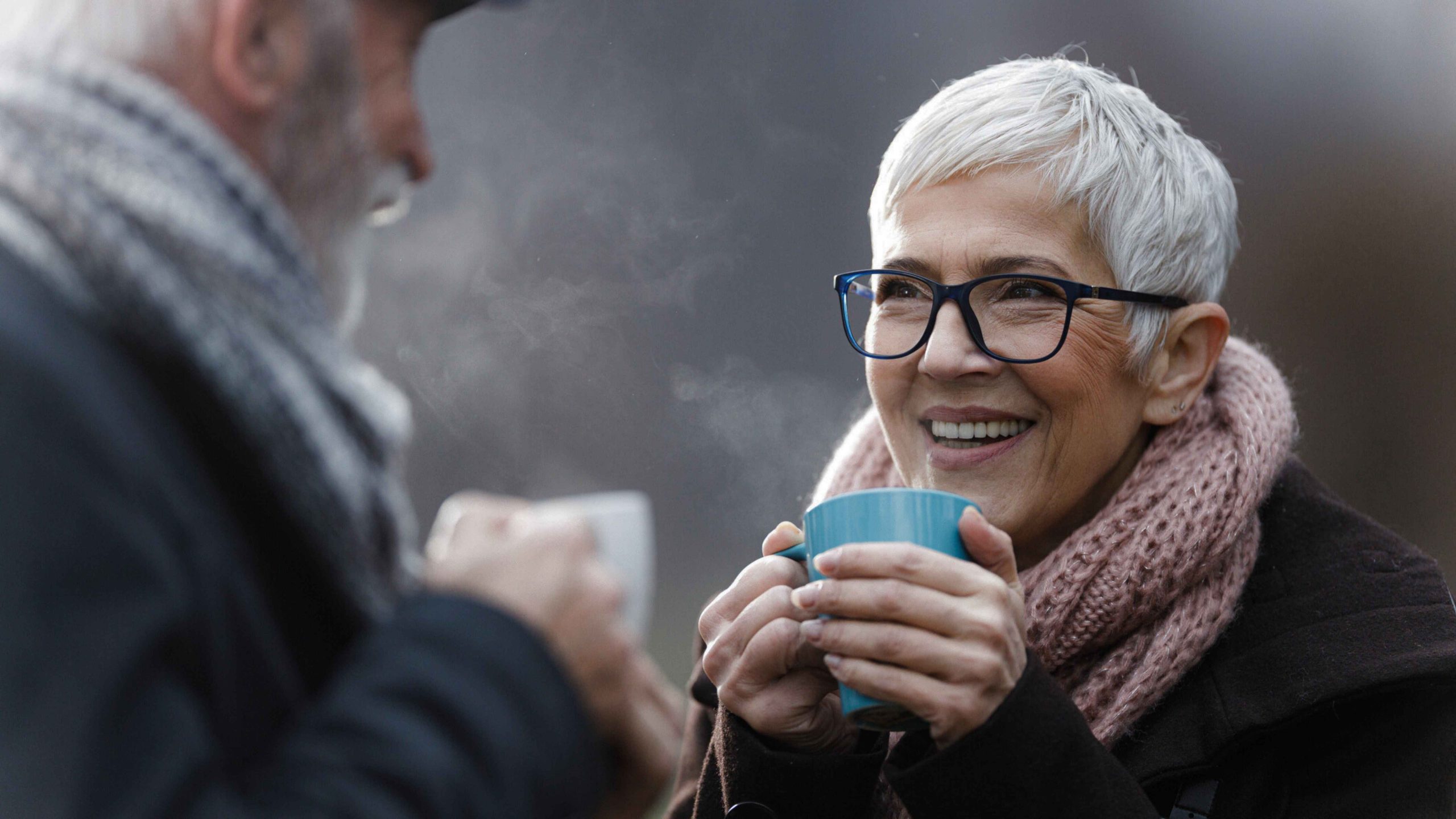 Elderly couple enjoying a hot beverage in the cold weather.